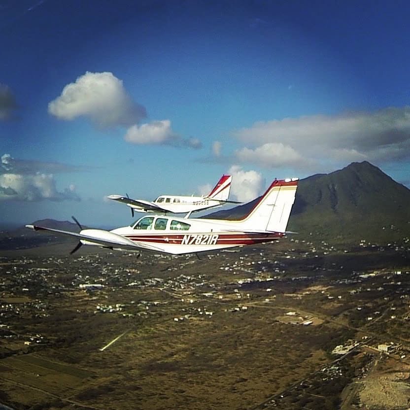 Two aircraft flying in formation over island terrain