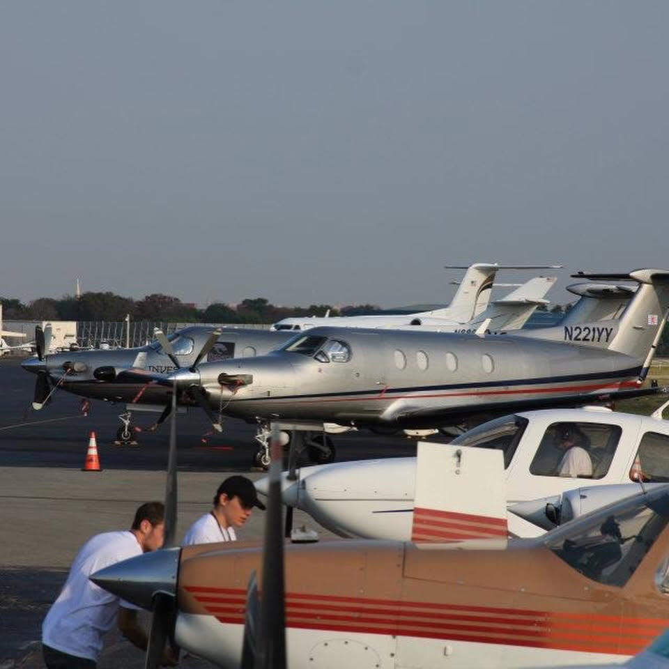 Private aircraft lined up on the ramp with crew preparing for departure